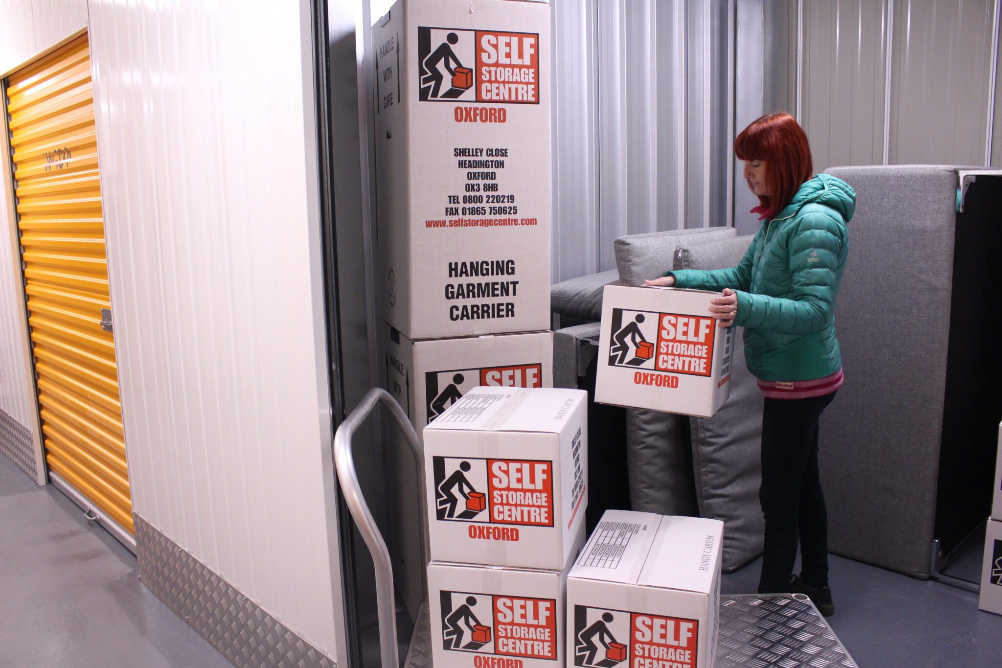 Woman in green jacket organizing her belonging inside her personal storage room